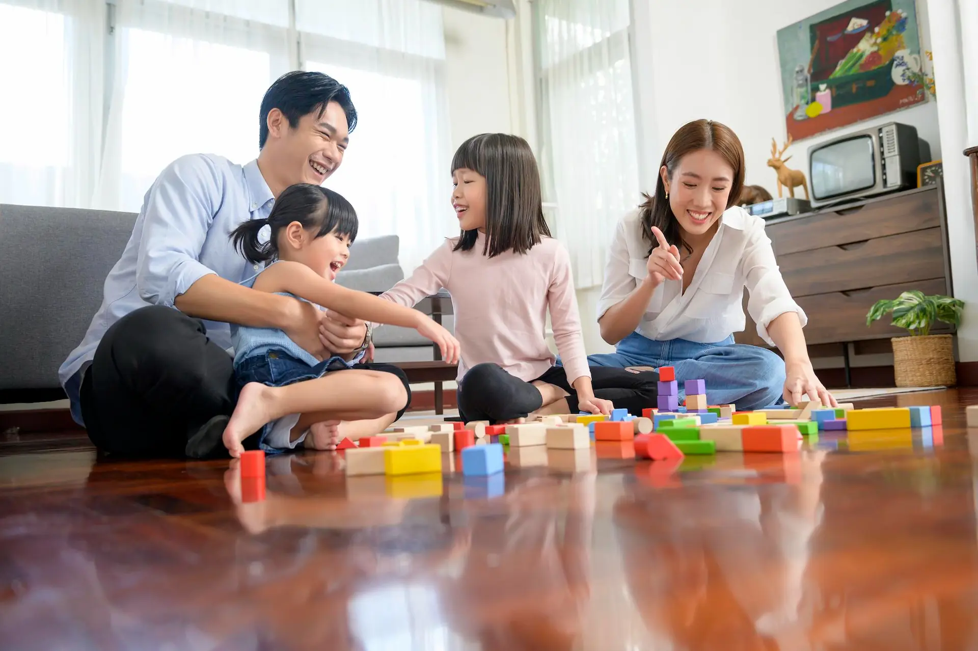 Asian family with children playing and building tower of colorful wooden toy blocks