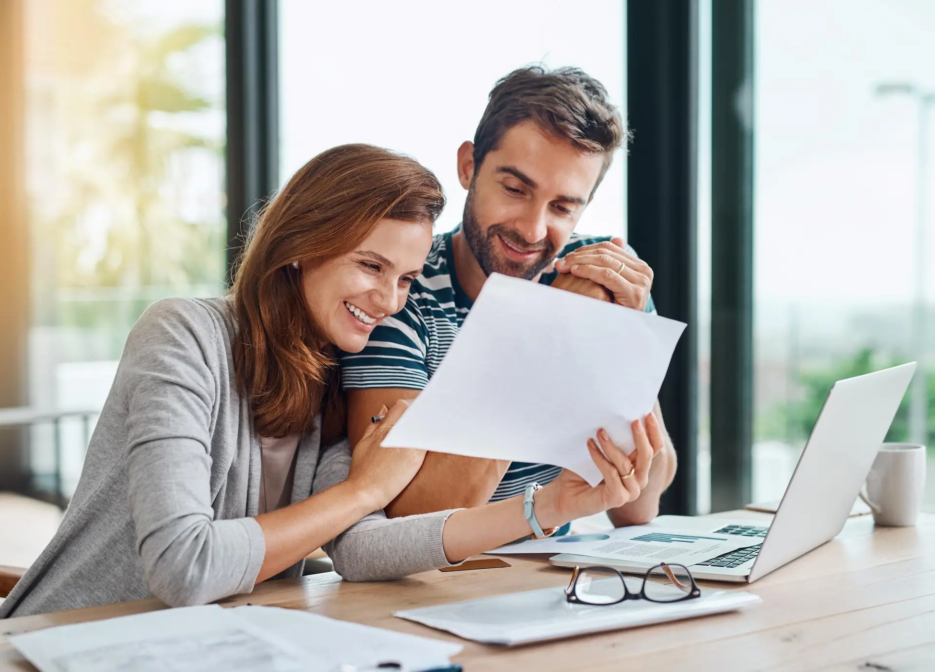 Documents finance and couple planning budget for tax bills and savings on lap
