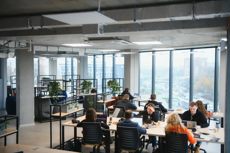 A group of people sit at tables in an open office space.